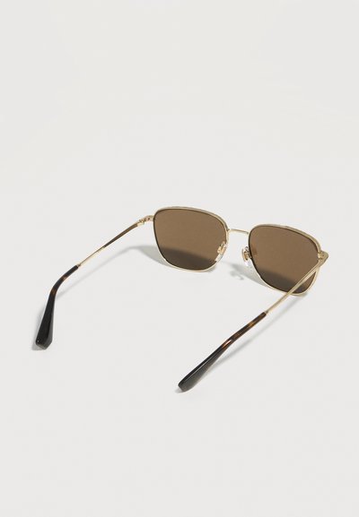 Ορθογώνια γυαλιά ηλίου με καφέ απόχρωση, λεπτά χρυσά πλαίσια και άκρες βραχίονα σε σχέδιο χελώνας, ανοιχτά τοποθετημένα σε λευκή επιφάνεια.