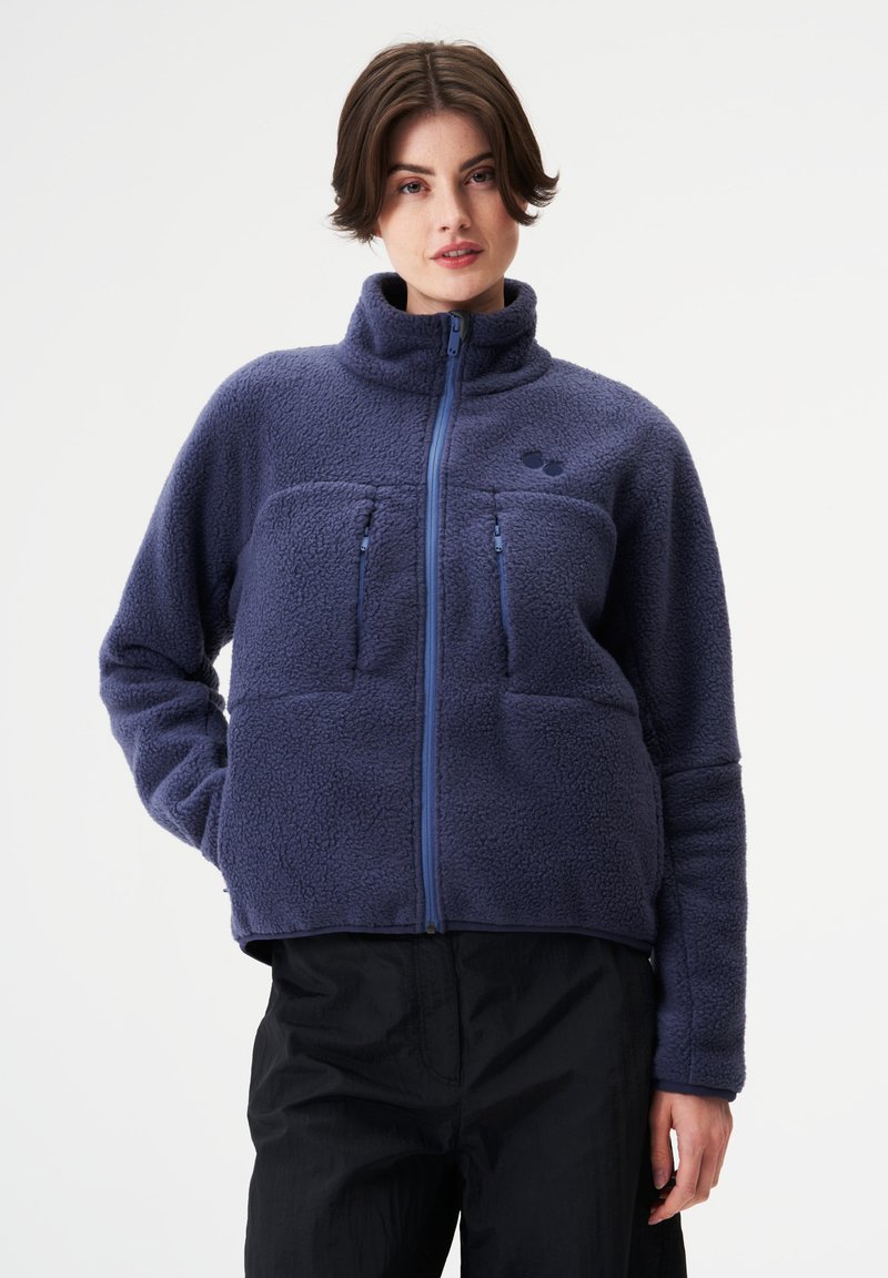 Marineblaue Fleecejacke mit hohem Kragen, Reißverschluss, zwei Fronttaschen und kontrastierenden blauen Reißverschlüssen. Strukturierte, weiche Außenseite.