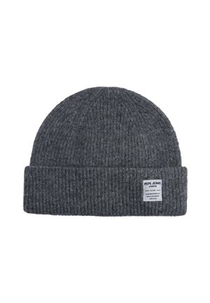 Gorro de punto gris con textura acanalada, que presenta un puño doblado y una etiqueta blanca que muestra detalles de la marca y el origen.
