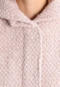 Lichtroze gemêleerde hoodiejack met een geweven patroon, voorzien van een voorkant sluiting, zachte stof en een gezellige uitstraling.