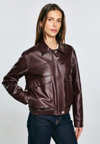 Burgunderfarbenes Kunstlederjacke mit Kragen, vorderem Knopfverschluss und zwei großen Taschen, mit geripptem Saum und strukturiertem Finish.