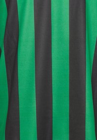 Maglia sportiva a righe verdi e nere realizzata in tessuto texturizzato, con righe verticali di larghezza uniforme, superficie liscia.