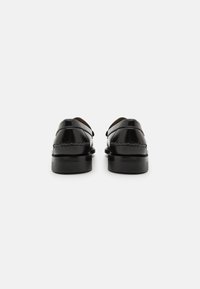 Sorte skinnloafers med en glatt overflate, rund form og kontrasterende sømmer. Har en lav profil gummisåle og klassisk design.