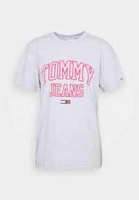Šedé bavlněné tričko s kulatým výstřihem a krátkým rukávem. Na přední straně se nachází nápis "TOMMY JEANS" tučnými červenými písmeny a malý logo detail na lemu.