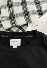 Svart T-shirt med rund hals och etikett "ta tid att drömma", i rutigt och rutmönstrat tyg i monokrom färg.
