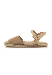 Sandal de ante marrón tipo slingback con puntera abierta redondeada, correa tejida dorada con hebilla y suela de yute trenzado. Diseño plano para mayor comodidad.
