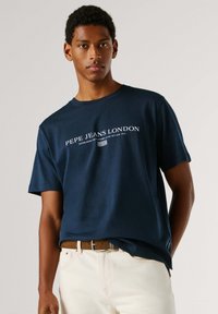 Μπλουζάκι από βαμβάκι σε ναυτικό μπλε με κοντά μανίκια, με λευκό λογότυπο κειμένου "Pepe Jeans London" στο εμπρός μέρος. Απλό σχέδιο χωρίς μοτίβα.