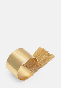 Kultaketjuinen kultainen rannekoru, jossa on leveä ja sileä nauha sekä cascadoituja hienoja ketjuosuuksia, luoden tekstuurisen ja kerroksellisen ilmeen.