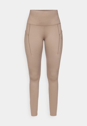 Beige sportleggings magas derekú kialakítással, két oldalsó zsebbel és sima, rugalmas anyaggal. Diszkrét, szürke logó részlet.