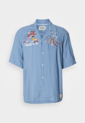 Cămașă albă cu mânecă scurtă, de culoare bleu deschis, cu închidere cu buton și modele brodate care reprezintă o floare de trandafir, soare, valuri și o clădire pe partea stângă.