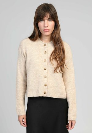 Cardigan beige en tricot avec col rond, sept boutons en bois sur le devant, manches longues et une taille courte. Texture douce.