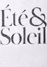Texte noir « Été & Soleil » en grande police serif avec une texture usée sur fond blanc.