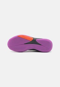 Semelle texturée violette et orange d'une chaussure de sport avec une section centrale noire montrant le logo Adidas sur fond blanc.