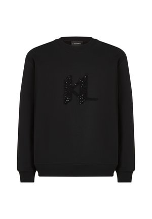 Czarna bluza wykonana z miękkiego materiału, z pluszowym czarnym logo "KL" ozdobionym cekinami. Okrągły dekolt, długie rękawy i ściągacze.