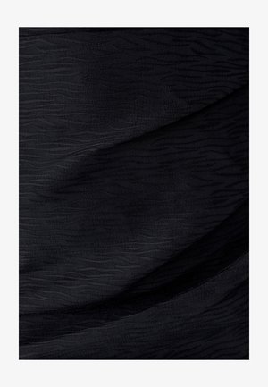 Černá tkanina s jemným vlnitým vzorem a texturovaným povrchem, ukazující měkký vzhled a splývavé záhyby.