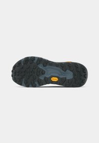 Semelle extérieure en caoutchouc noir avec des crampons profonds pour la traction, présentant une semelle intermédiaire bleue et un logo Vibram jaune. Design texturé pour la durabilité.
