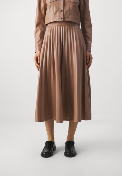 Brun plisserad kjol i konstläder, midikalvlängd, matchad med en kort läderjacka och svarta loafers.