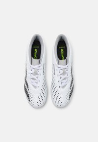 Scarpe da calcio bianche con un design elegante, caratterizzate da una striscia nera e da motivi a pois. Materiale leggero con una texture liscia.
