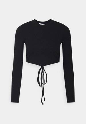 Zwarte cropped top met lange mouwen, ronde hals en een gestrikte detail aan de voorkant, losjes hangend tegen een effen lichte achtergrond.
