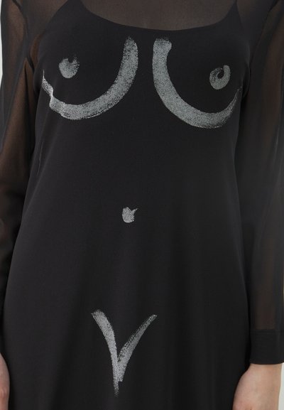 Sorte kjole lavet af blødt stof med sølv abstrakte designs, der ligner bryster og en nedadgående trekant i midten. Gennemsigtige lange ærmer.
