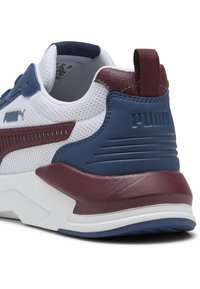 Sneaker z białą siateczkową cholewką, granatowymi akcentami i bordowym piętą. Posiada teksturowane panele oraz gumową podeszwę z logo PUMA.