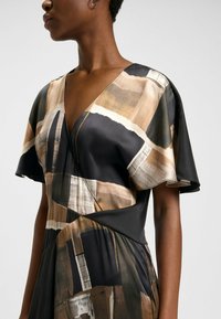 Robe en satin avec un décolleté en V profond, des manches courtes volantées, et un motif abstrait marron et noir avec une texture lisse et une drape élégante.