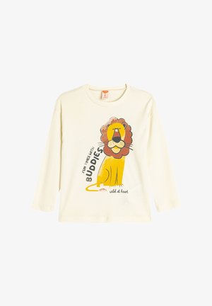 Camiseta de manga larga color crema con un gráfico de un león de dibujos animados con melena marrón y el texto "DIVERTIDOS MOMENTOS CON AMIGOS" en negro y amarillo.