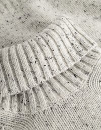 Cremefarbener Strickpullover mit geripptem Kragen, der im gesamten Stoff mit schwarz gesprenkeltem Garn für Textur und Detail versehen ist.