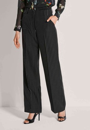 Zwarte wijde broek met krijtstreep en zijzakken, gecombineerd met glanzende zwarte open-toe hakken. Glad materiaal met een getailleerde pasvorm.