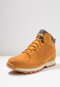 Bruine leren wandelschoen met grijze accenten, ronde neus, oranje veters, rubberen zool en geborduurd logo op de zijkant.