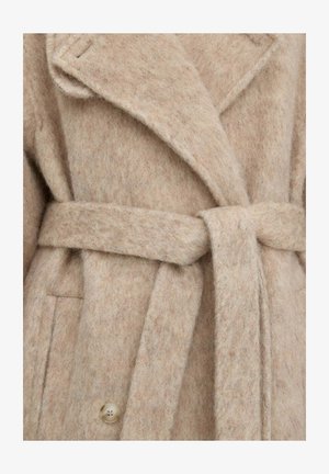 Béžový vlněný kabát se širokými klopami, zavazovacím pásem v pase a viditelným knoflíkem blízko spodní části na přední straně.