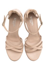 Beżowe sandały na obcasie z gładkiej skóry, z paskiem wokół kostki i krzyżującymi się paskami na palcach. Posiadają wyściełaną wkładkę.
