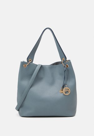 Sac à main en cuir bleu texturé avec doubles poignées, bandoulière réglable et pendentif rond doré avec logo.