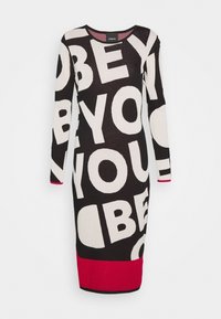 Schwarzes Strickkleid mit auffälligem weißem Text „OBEY“ und „YOU“ in verschiedenen Größen, mit einem roten unteren Saum und kontrastierenden Ärmelakzenten.