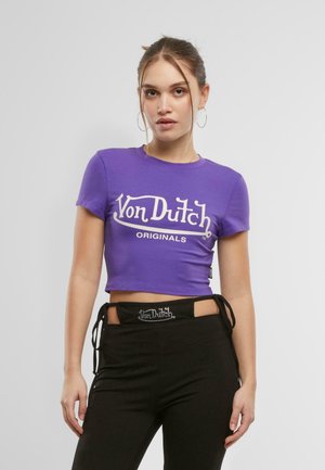 Violets krūšturis no kokvilnas ar īsām piedurknēm. Priekšā ir balta "Von Dutch Originals" grafikā skriptveida fontā.