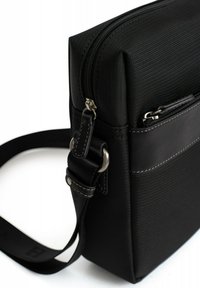Borsa a messaggero nera con tessuto testurizzato e dettagli in pelle. Dotata di chiusura con zip, tracolla regolabile e tasca esterna per lo stoccaggio.