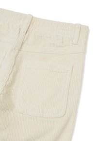 Crèmekleurige corduroy stof, met verticale ribbels, een elastische tailleband en een enkele achterzak met afgeronde hoeken.
