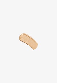 Échantillon de crème cosmétique beige avec une texture lisse, présentant de subtiles ondulations et une finition légèrement brillante sur un fond blanc.