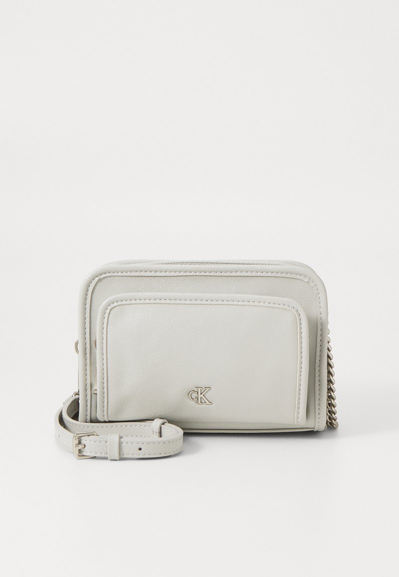 White faux leather crossbody bag with a textured surface, featuring a front pocket, chain accent, and adjustable strap.