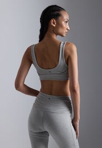 Grå atletisk crop top og høydejusterte leggings med rynkedetaljer. Glatt tekstur, minimal merking og tettsittende passform.