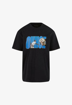 Juodas medvilnės marškinėliai su grafiniu dizainu, kuriame pavaizduota paukštis ir tekstūruotas pelėda, nudažyti balta ir ruda spalvomis, su ryškiai mėlynomis raidėmis.