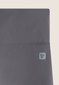 Tejido atlético gris con una textura suave, que presenta un pequeño logotipo en un cuadrado en la esquina inferior derecha. Diseño sencillo con una costura en el medio.