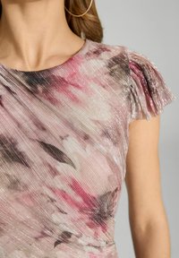 Robe à imprimé floral dans des tons de rose et de crème avec une texture plissée et des accents brillants. Des manches courtes à franges complètent le design.