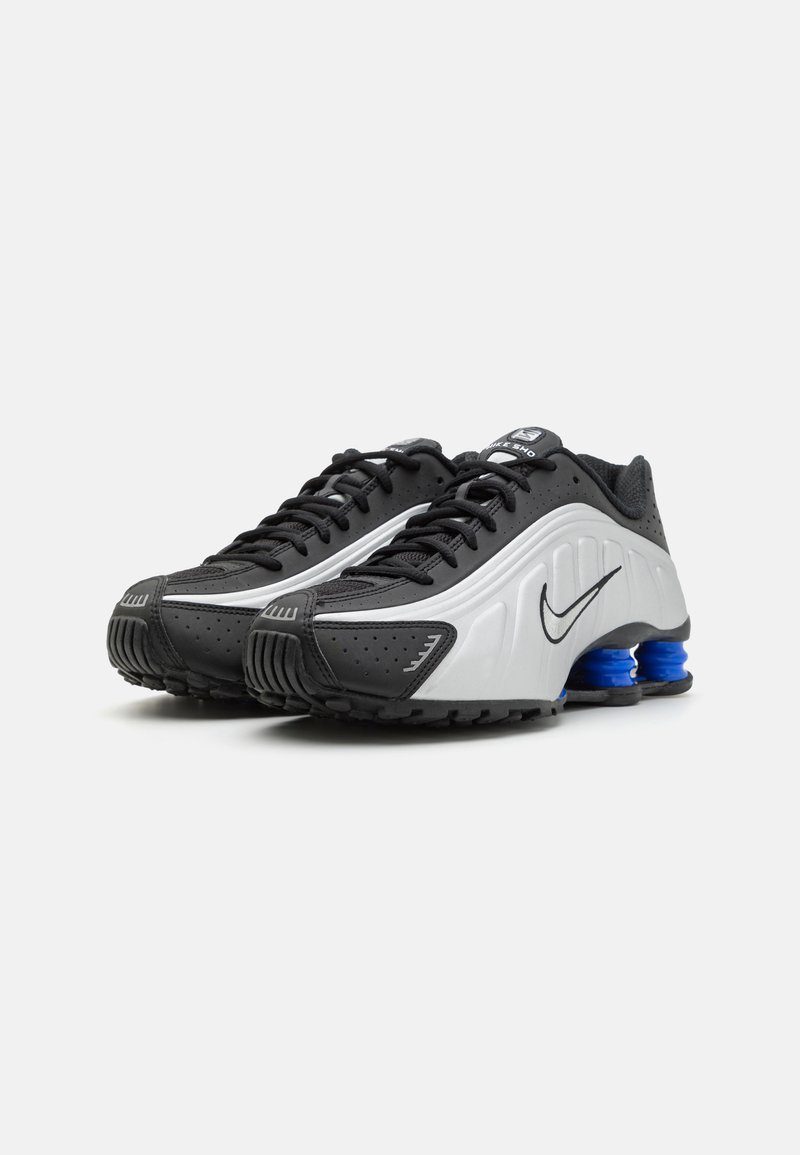 Chaussures de sport noires et argentées avec une tige texturée, un bout arrondi et des accents de rembourrage bleu. Présente des perforations et un design à lacets.