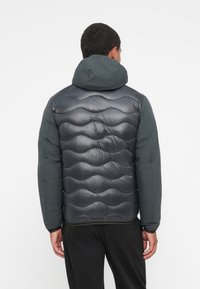 Padded jacket with a hood, featuring a wavy quilted design in dark gray and a matte finish. Elastic cuffs and a contrasting hem detail.