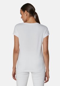 Witte korte mouwen t-shirt met een ruime pasvorm, ronde halslijn en opgerolde mouwen. De stof lijkt glad en lichtgewicht.