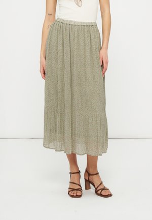 Lahkotna dolgo rjavkasto zelena krilo z drobnim cvetličnim potiskom, do gležnja, nošeno z belo majico in rjavimi sandalami z naramnicami ter širokim peto.