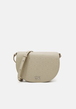 Sac bandoulière beige avec sangle réglable, motif répétitif embossé "CK" et logo argenté "CK" sur le rabat avant.