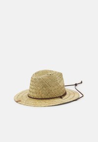 Olkipäähattu, jossa on leveä reuna, herringbone-kuvio, tummanruskea säädettävä naru ja pyöreä huippu. Vaalean tanin väri.