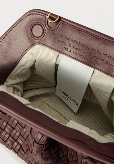 Burgundska prepletena usnjena torbica z gladkim notranjim podlogom. Ima zlati okrogli varnostni obroč in oznako, ki se glasi "THEMOIRÉ MADE IN ITALIJI."